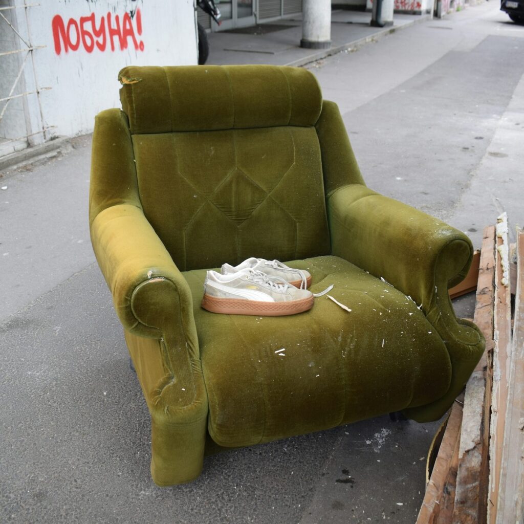 Discarded upholstered armchair and household items ready for removal, representing dumpster rental services near me.
