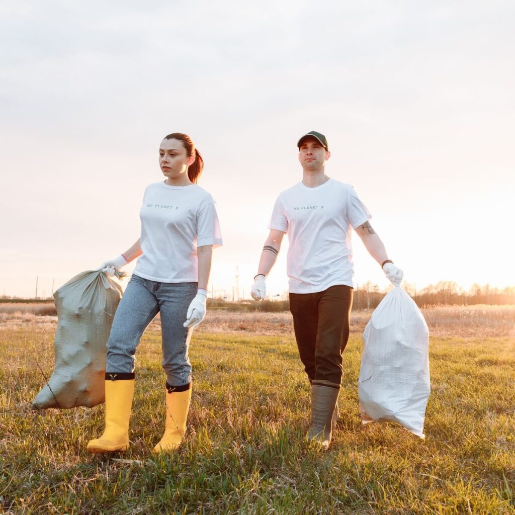 Cleanup workers carrying bags of collected debris for dumpster rental projects in Shelby, MI