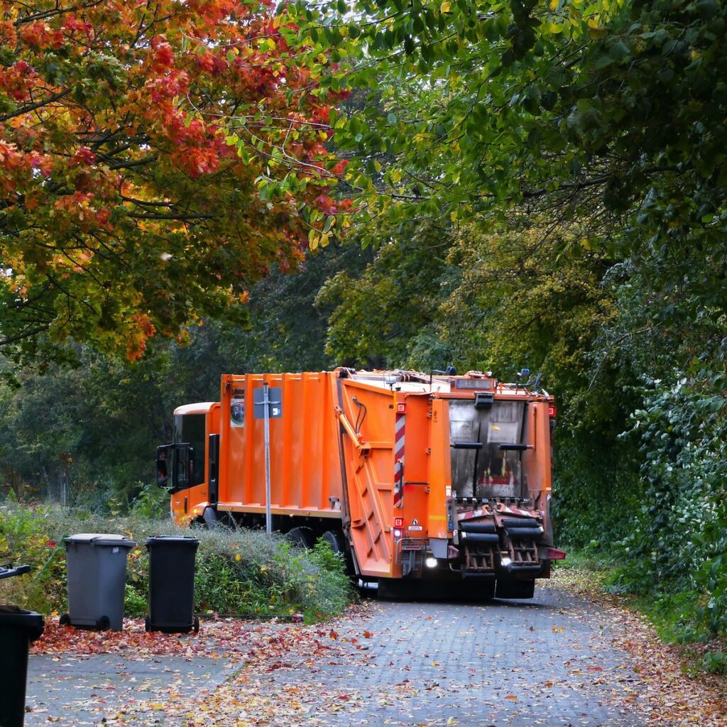 Waste collection truck servicing residential bins for dumpster rental and cleanup services near me