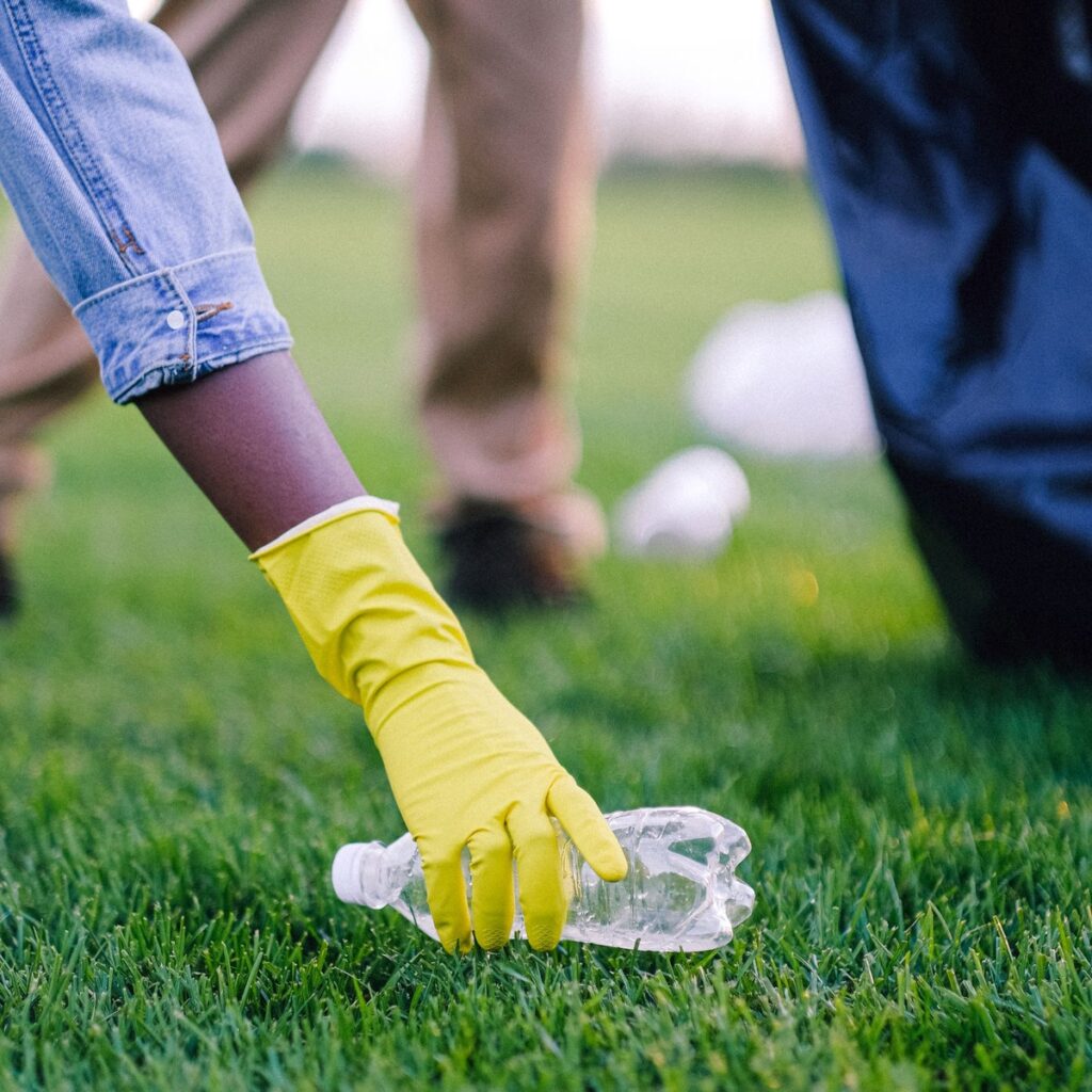 Gloved hand collecting a plastic bottle during property cleanup in New Era, MI
