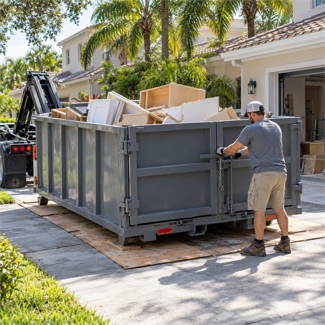Worker securing the rear door of a roll-off dumpster filled with discarded cabinets and renovation debris during dumpster rental services near me